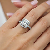 Dawn - princess cut diamond halo ring with diamonds in the band in platinum. Displayed on a lady's hand